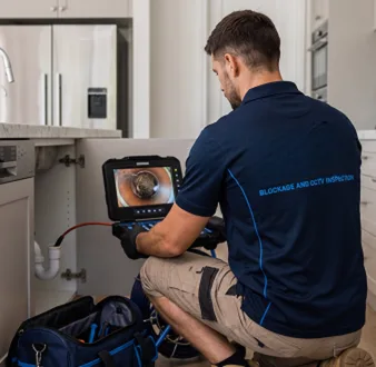 Plumber clearing a blocked toilet in a Mortlake bathroom